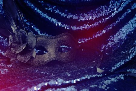 Photo of elegant and delicate black Venetian mask over dark sequins fabric backgroundの写真素材