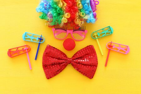 carnival, party and Purim celebration concept (jewish carnival holiday) with clown wig, glasses and red nose over yellow backgroundの写真素材