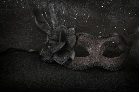 Photo of elegant and delicate black Venetian mask over dark glitter backgroundの写真素材