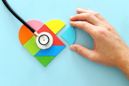 Heart puzzle and with stethoscope on blue pastel wooden background, medical conceptの写真素材