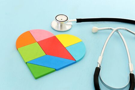Heart puzzle and with stethoscope on blue pastel wooden background, medical conceptの写真素材