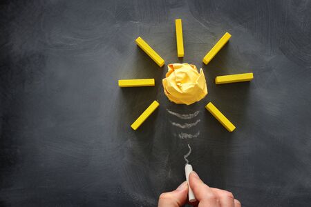 Education concept image. Creative idea and innovation. Crumpled paper as light bulb metaphor over blackboardの写真素材