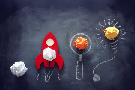 education or innovation concept. Wooden rocket over blackboard background. top view