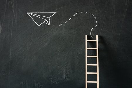 wooden ladder and sketch plane over classroom blackboard backgroundの写真素材