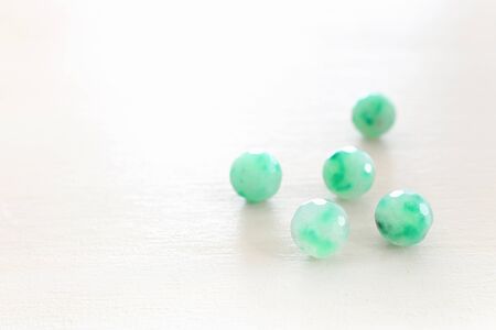 green gemstones beads on white wooden backgroundの写真素材