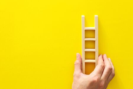 wooden ladder over yellow backgroundの写真素材