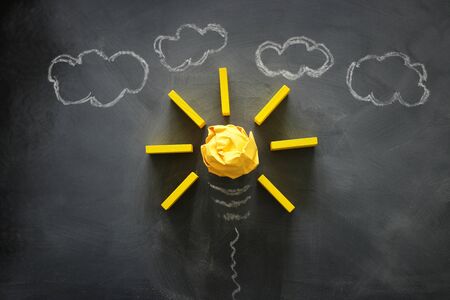 Education concept image. Creative idea and innovation. Crumpled paper as light bulb metaphor over blackboardの写真素材