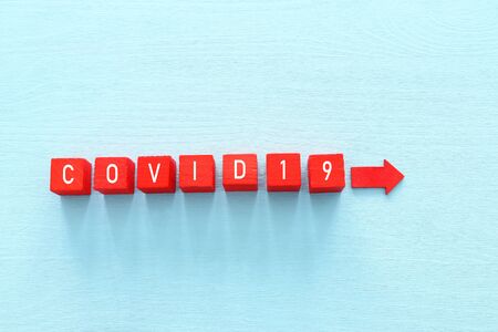 concept image of coronavirus idea. red wooden cubes with the text covid 19 over blue background