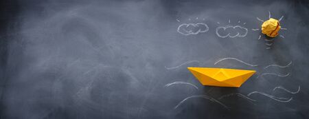 banner of single paper boat over blackboard background