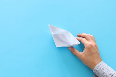 male hand directing single papaer boat on blue background. concept of finding the right directon and moving ahead.の写真素材