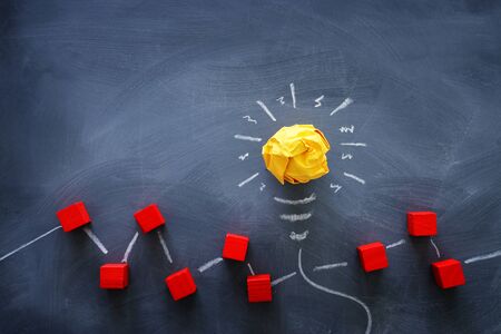 Education concept image. Creative idea and innovation. Crumpled paper as light bulb metaphor over blackboardの写真素材
