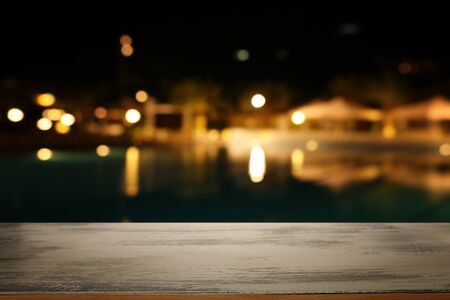 background Image of wooden table in front of abstract blurred restaurant lights
