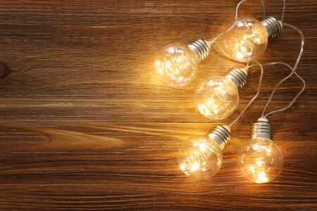 Light bulb lamps with warm light over old wooden backgroundの写真素材