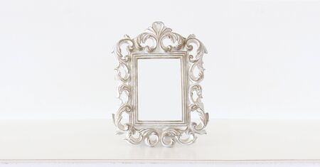 Image of white baroque vintage empty photo frame over wooden table. For mockup, can be used for...