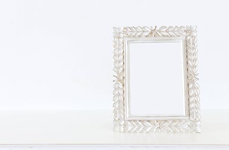 Image of white baroque vintage empty photo frame over wooden table. For mockup, can be used for photography montageの写真素材