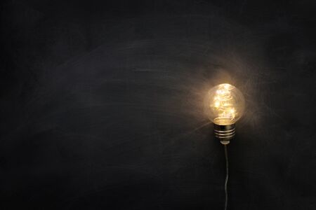 Education concept image. Creative idea and innovation. Light bulb as metaphor over blackboardの写真素材