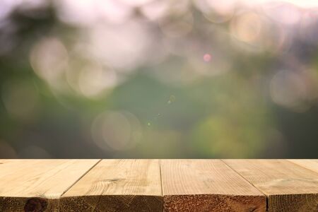 Empty rustic table in front of green spring abstract bokeh background. product display and picnic...