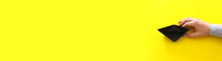 male hand directing single papaer boat on yellow background. concept of finding the right directon...