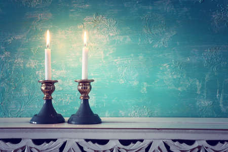 two shabbat candlesticks with burning candles over wooden tableの写真素材