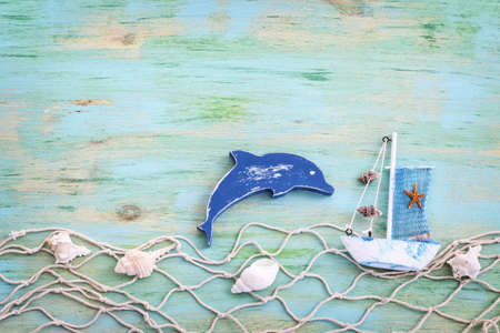 wooden vintage boat, dolphin, fishnet and sea shells over blue backgroundの写真素材