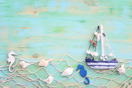 nautical concept with white decorative sail boat, seashells over blue wooden backgroundの写真素材