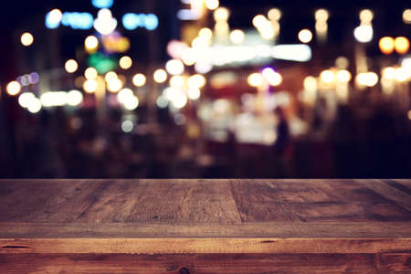 background Image of wooden table in front of abstract blurred restaurant lights