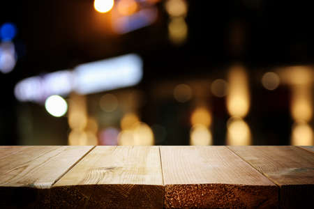 background Image of wooden table in front of abstract blurred restaurant lightsの写真素材