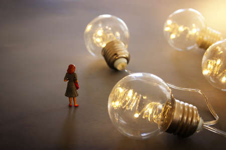 Surreal image of people looking at glowing light bulbs. Concept of finding the right idea, or solutionの写真素材