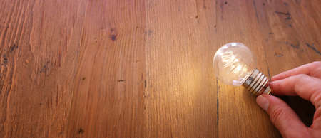 Education and innovation concept . Creative idea . male hand holding light bulb over wooden table