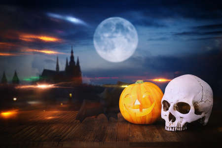 holidays halloween concept image. Pumpkin and skull over wooden table and scarry night castle backgroundの写真素材