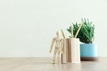 Stylish and minimal workplace with plant, pencils stand and dummy over wooden desk workの写真素材
