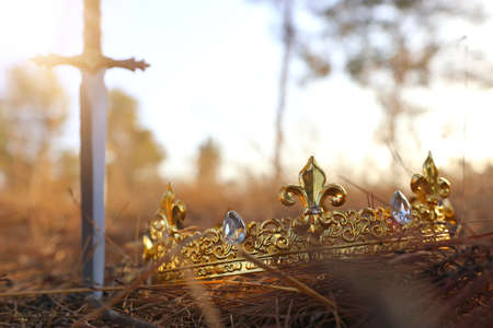 mysterious and magical photo of gold king crown and sword in the England woods. Medieval period...