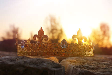 mysterious and magical photo of gold king crown in the England woods over stone. Medieval period...