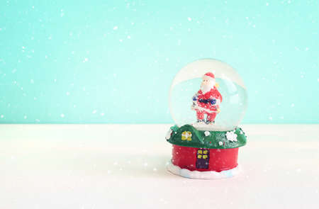 Image of christmas snow glass ball with santa claus in front of pastel blue backgroundの写真素材
