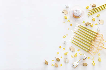 Image of jewish holiday Hanukkah with menorah (traditional Candelabra), donut and wooden dreidel...