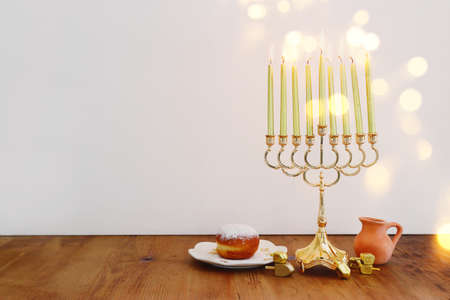 Image of jewish holiday Hanukkah with menorah (traditional Candelabra), donut and wooden dreidel (spinning top)の写真素材