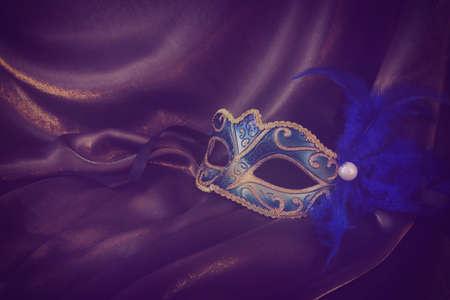 Photo of elegant and delicate gold Venetian mask over dark silk background. vintage filteredの写真素材