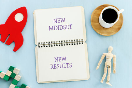 top view image of table with open notebook and the text new mindset new results. success and...