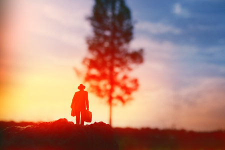 Surreal image of mysterious man walking alone in field during sunsetの写真素材