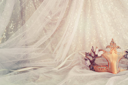 Photo of elegant and delicate Venetian mask over gold and blue chiffon backgroundの写真素材