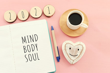 Flat lay image of notebook with words Mind, Body, Soul on pink wooden backgroundの写真素材