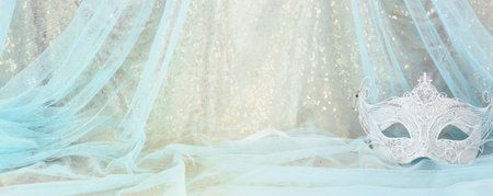 Photo of elegant and delicate Venetian mask over gold and blue chiffon backgroundの写真素材