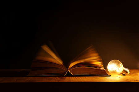 Magical image of open antique book over wooden tableの写真素材