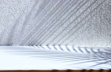 Textured wall with Palm tree shadow and wooden white table. Product display and presentation...