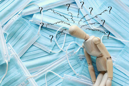 image of wooden dummy with worried stressed thoughts. over protective face mask background. anxiety...