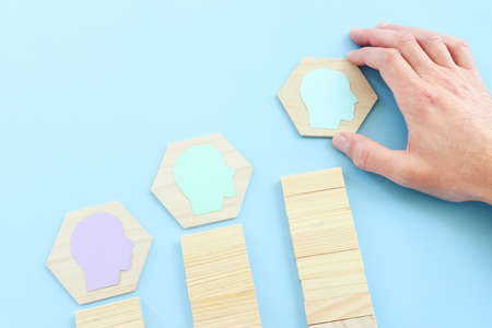 wooden blocks with people icon over blue background, building a strong team, human resources and management conceptの写真素材