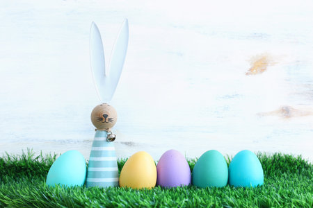 Cute bunny next to easter colorful eggs over pastel background