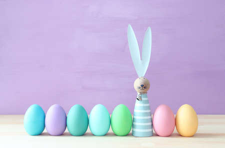Cute bunny next to easter colorful eggs over pastel backgroundの写真素材