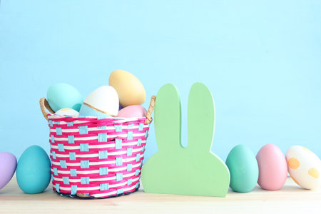 Cute bunny next to easter colorful eggs over pastel background