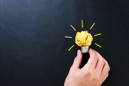 Education concept image. Creative idea and innovation. Crumpled paper as light bulb metaphor over black backgroundの写真素材